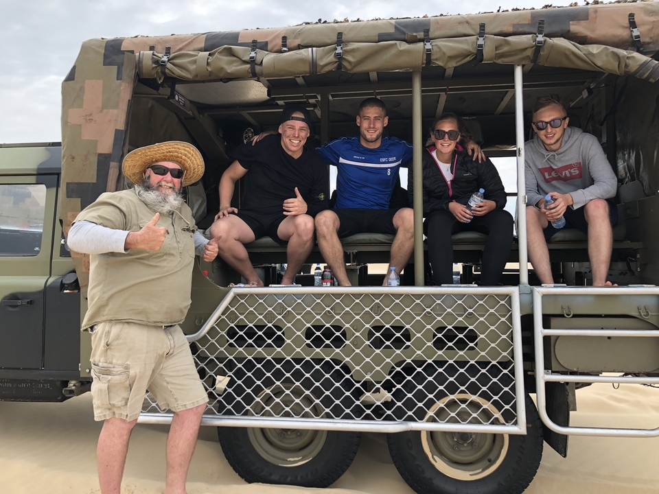 Groupe de personnes assises dans un véhicule ouvert posant pour une photo.