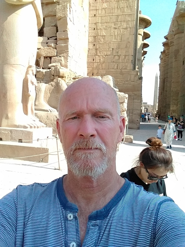 Gros plan d'une personne posant devant des ruines de l'Égypte antique.