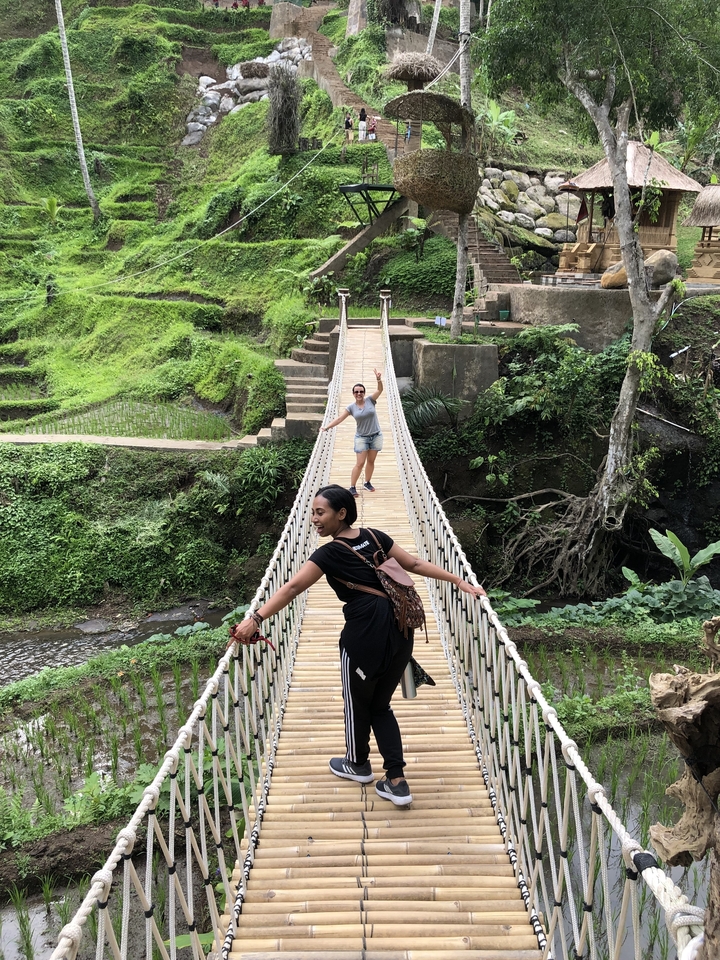 Deux femmes posant sur un pont en bois au milieu de la verdure.