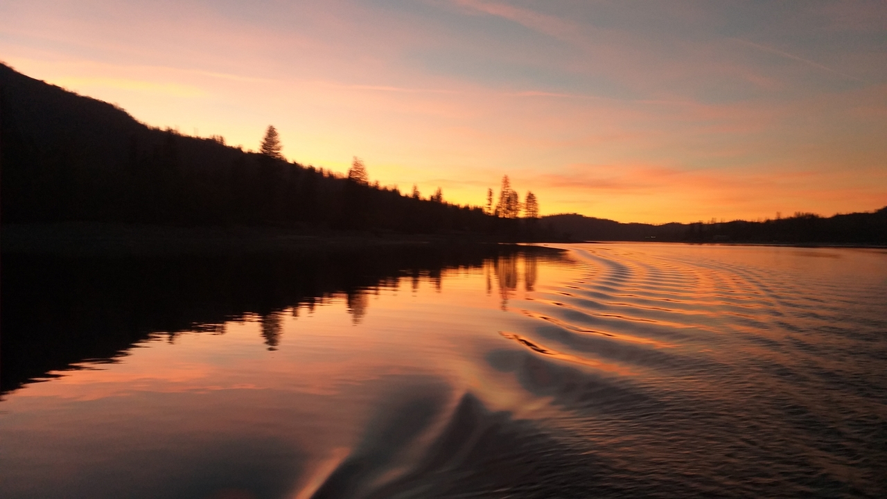 Coucher de soleil sur un lac avec reflet et ondulations.