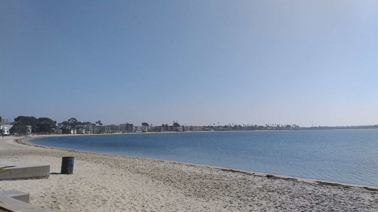 Une plage calme sous un ciel bleu clair avec une vue lointaine de la ville.