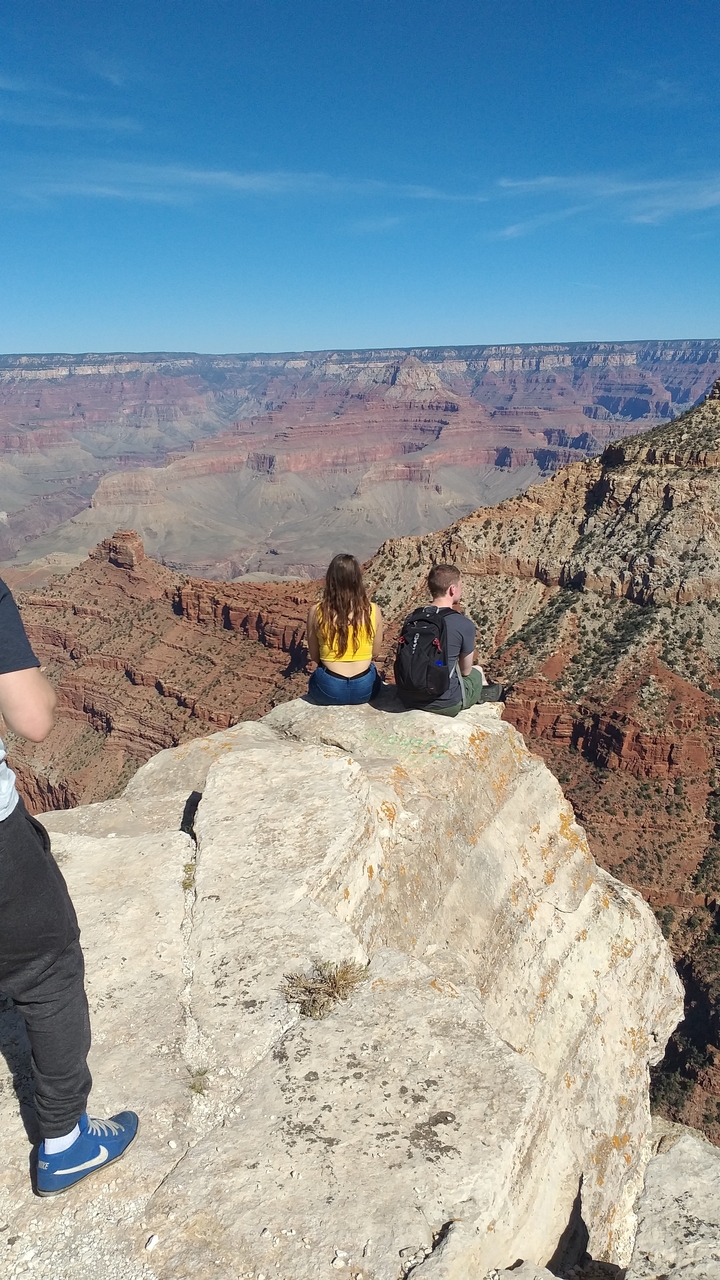 Deux personnes assises qui profitent d'une vue sur le Grand Canyon.