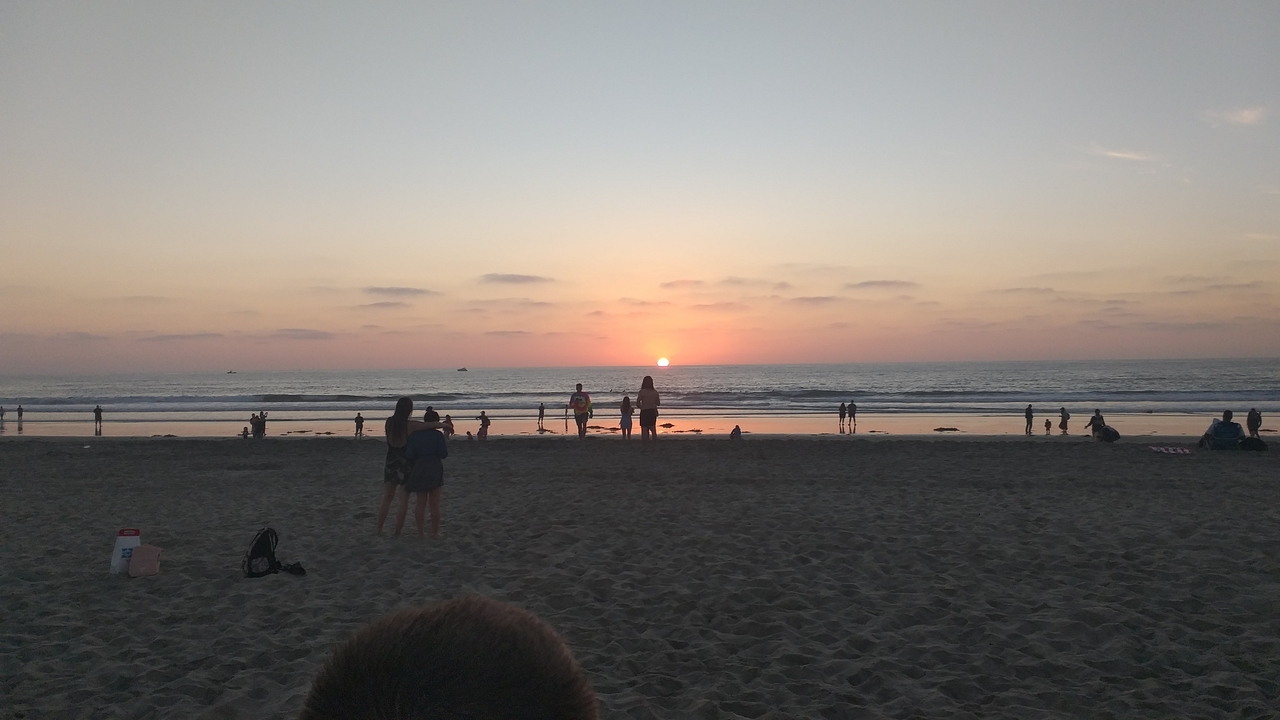 Des gens sur une plage regardant le coucher de soleil.