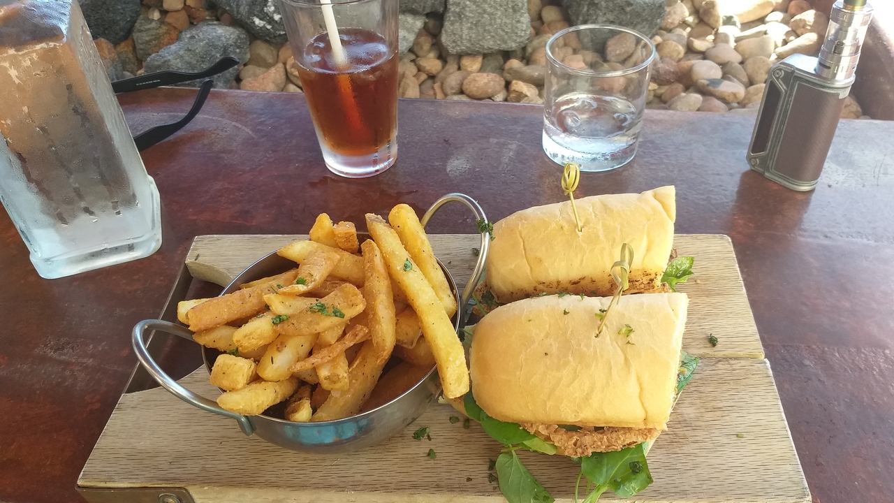 Nourriture servie à une table extérieure avec des frites et des sandwichs.