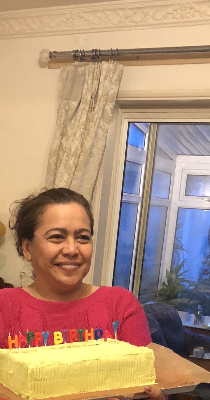 Personne souriante à l'intérieur d'une pièce près d'une fenêtre.