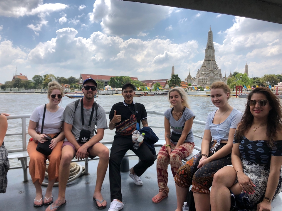 Group of people on a boat with a temple in the background.
