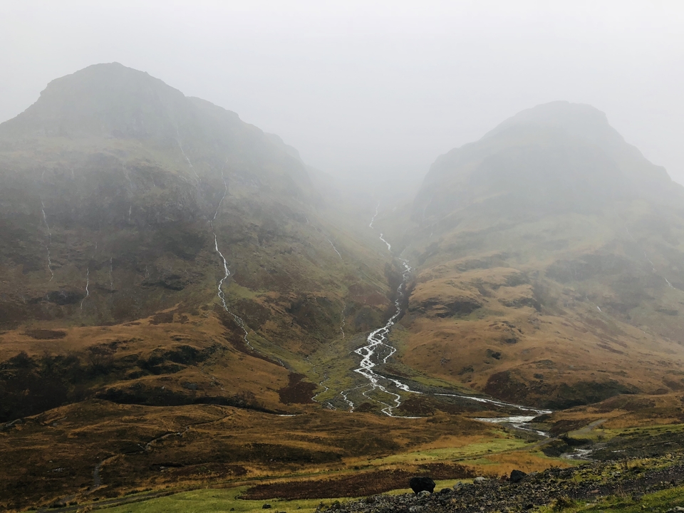 Moody landscape with two mountains and a winding stream.