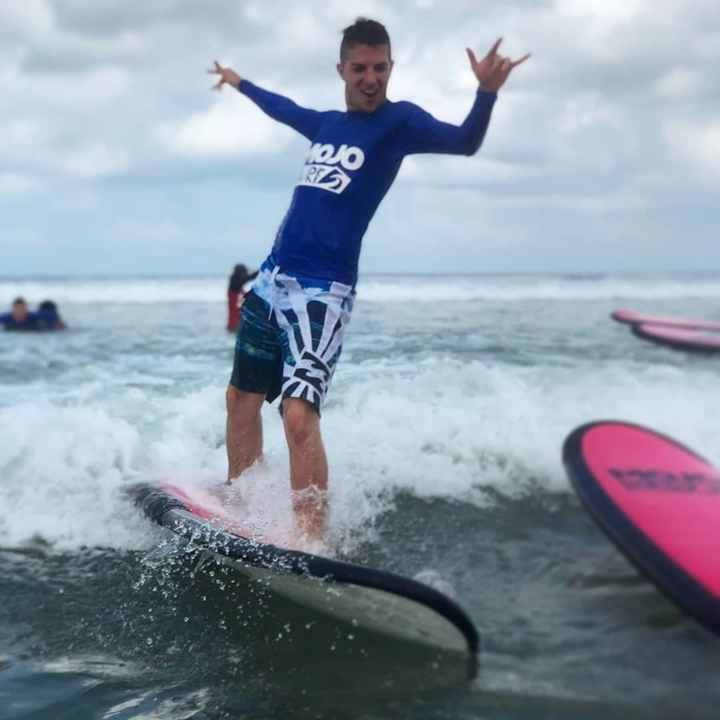 Person standing on a surfboard riding a wave.