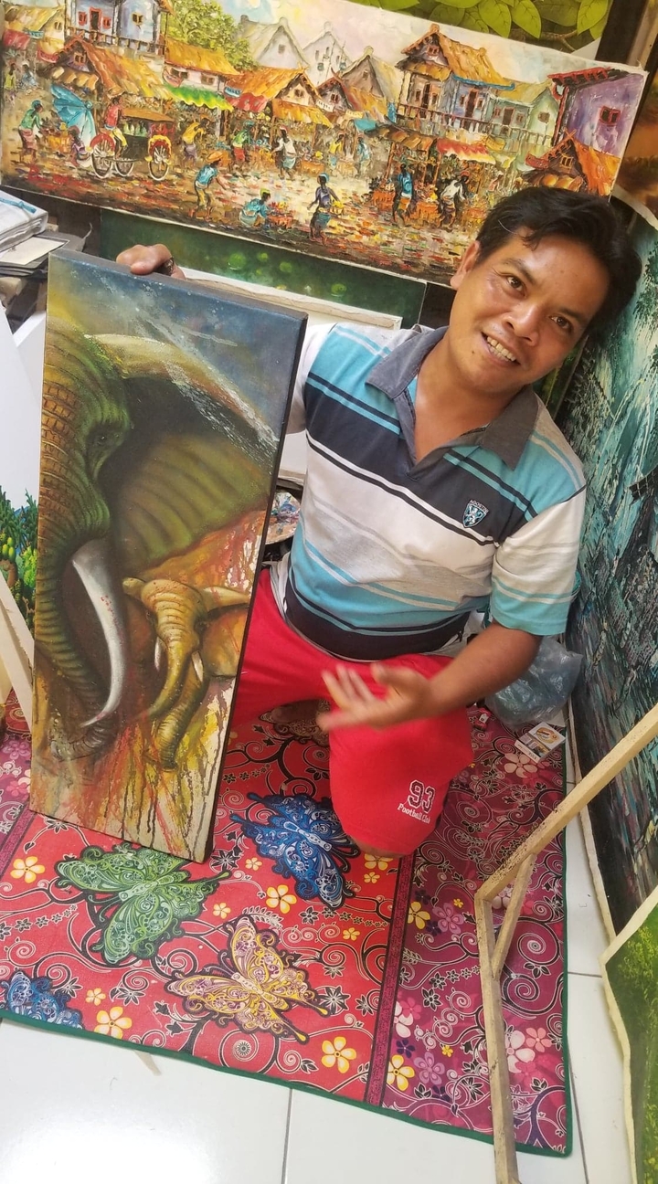 Une personne tenant une peinture d'un éléphant.