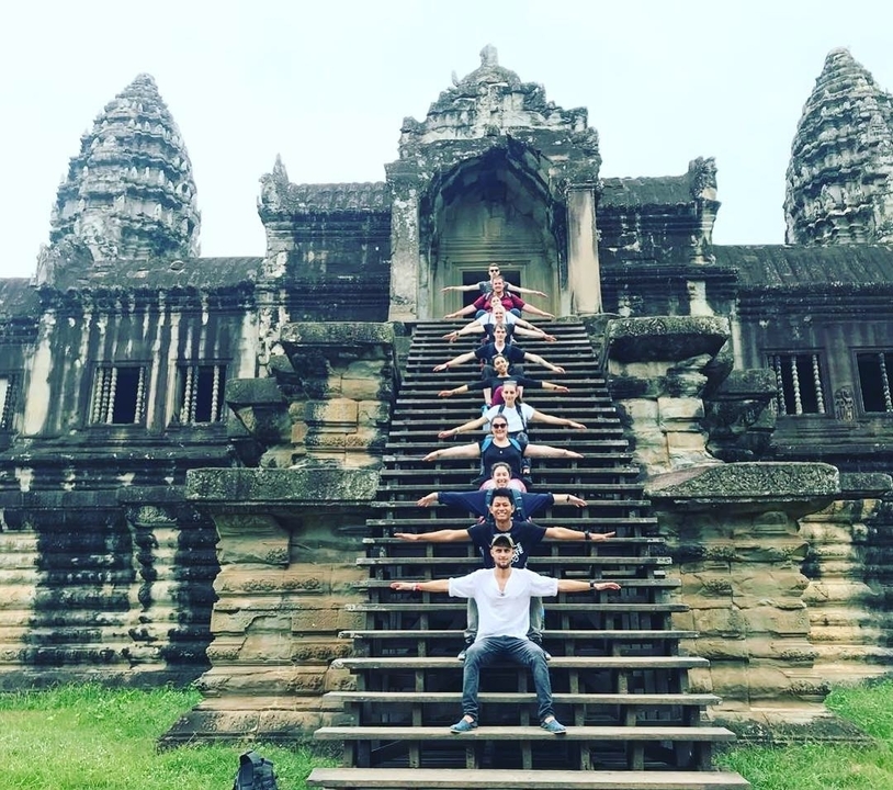 People standing in a line on steps of a temple with arms extended outward.