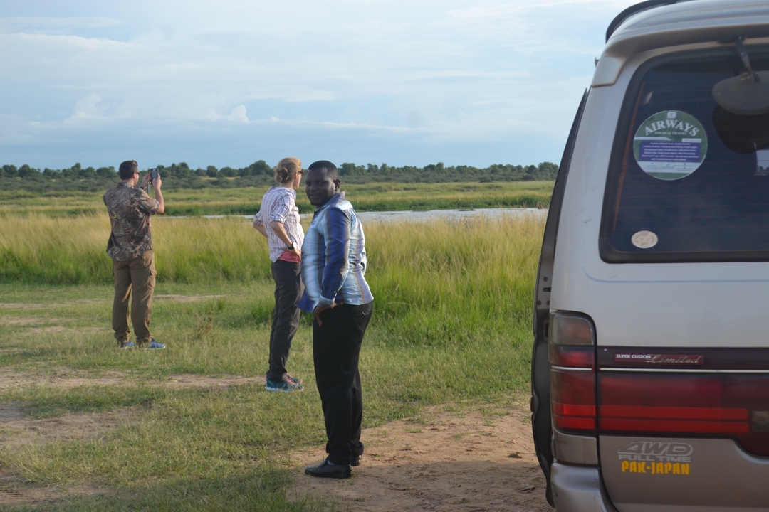 Des gens debout près d'un véhicule garé dans un champ herbeux ouvert.