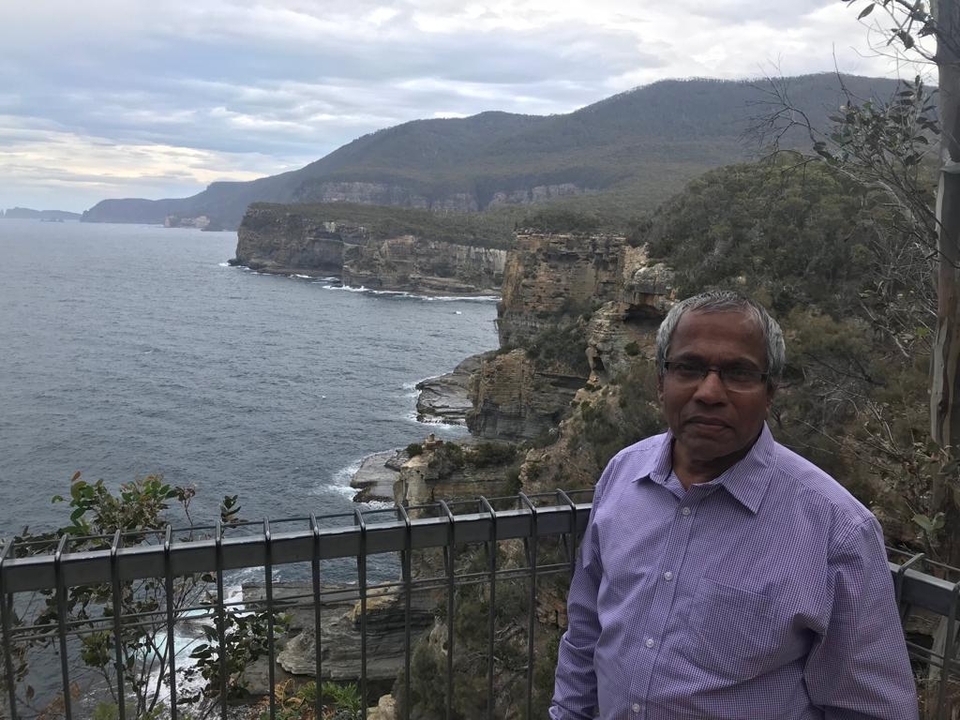 Une personne debout sur une falaise escarpée avec l'océan en arrière-plan.