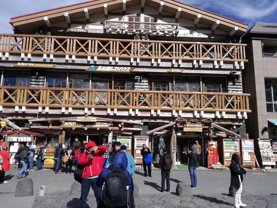 Des gens se sont rassemblés devant un bâtiment avec des panneaux et des distributeurs automatiques.