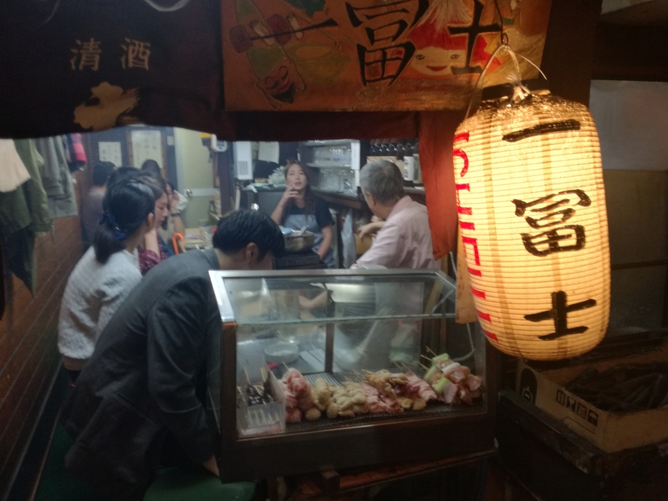 Des gens qui dînent à l'intérieur d'un petit restaurant avec une lanterne japonaise.