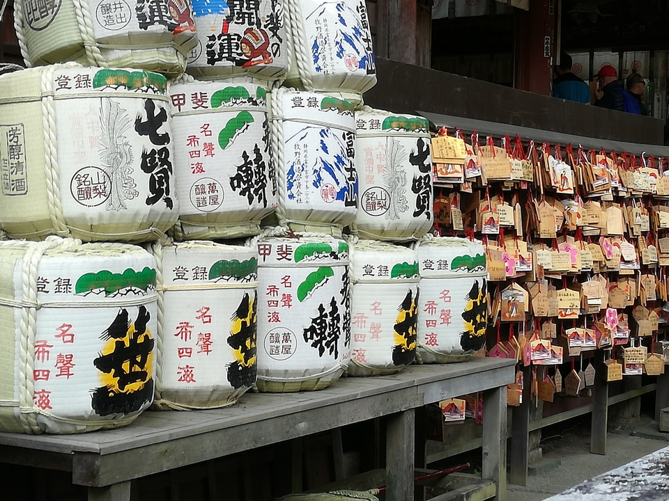 Tonneaux de saké décoratifs et plaques ema dans un temple.