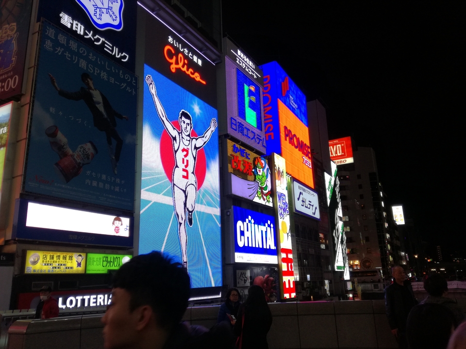 Panneaux d'affichage illuminés dans un quartier urbain animé la nuit.