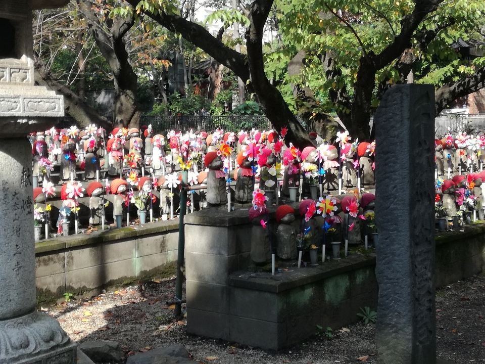 Statues de pierre avec des moulins à vent colorés et des chapeaux dans un parc.