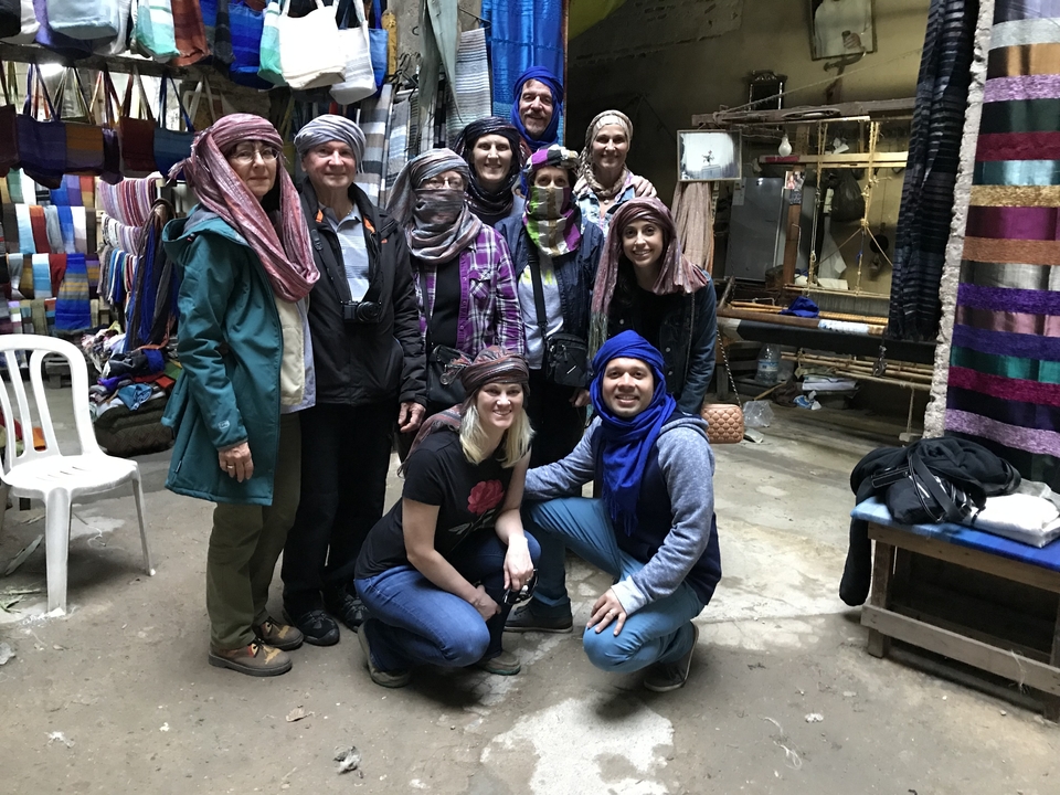Groupe de personnes posant dans un marché textile avec des foulards colorés.