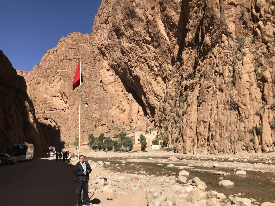 Grande canyon avec une rivière, personne debout près du drapeau marocain.