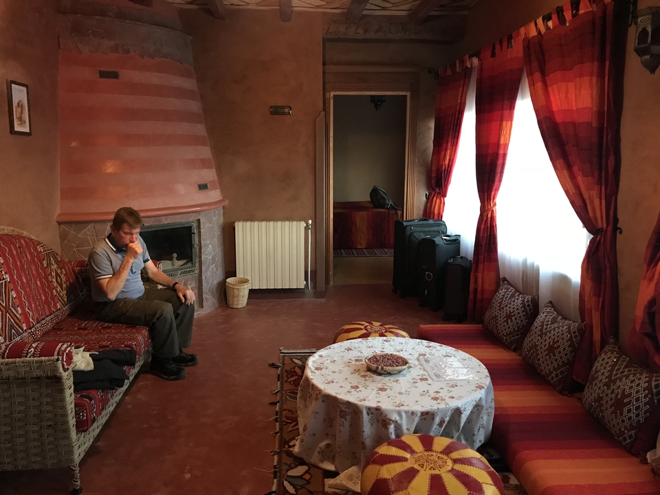 Un homme assis dans une pièce confortable avec une décoration traditionnelle et une cheminée.