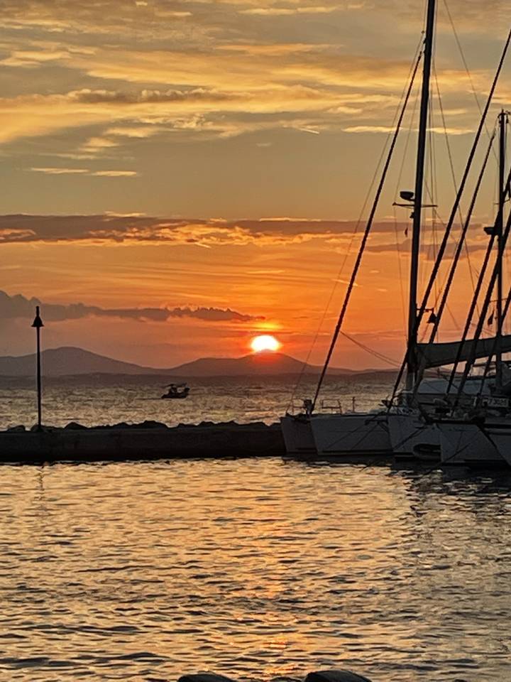 Sunset over the sea with a boat silhouette.