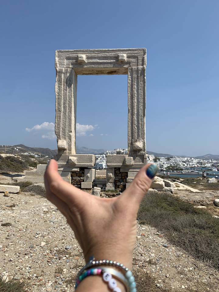 Person holding landmark stone structure against a backdrop.