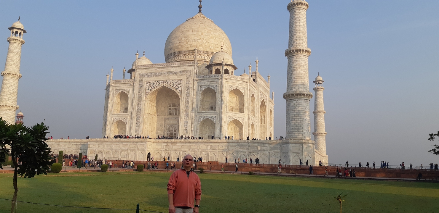 Un homme posant devant le Taj Mahal, un célèbre monument indien.