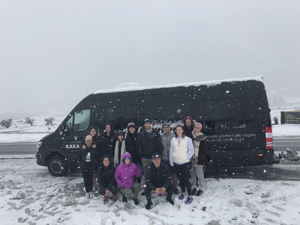 Groupe de personnes posant devant un van de tourisme dans la neige.