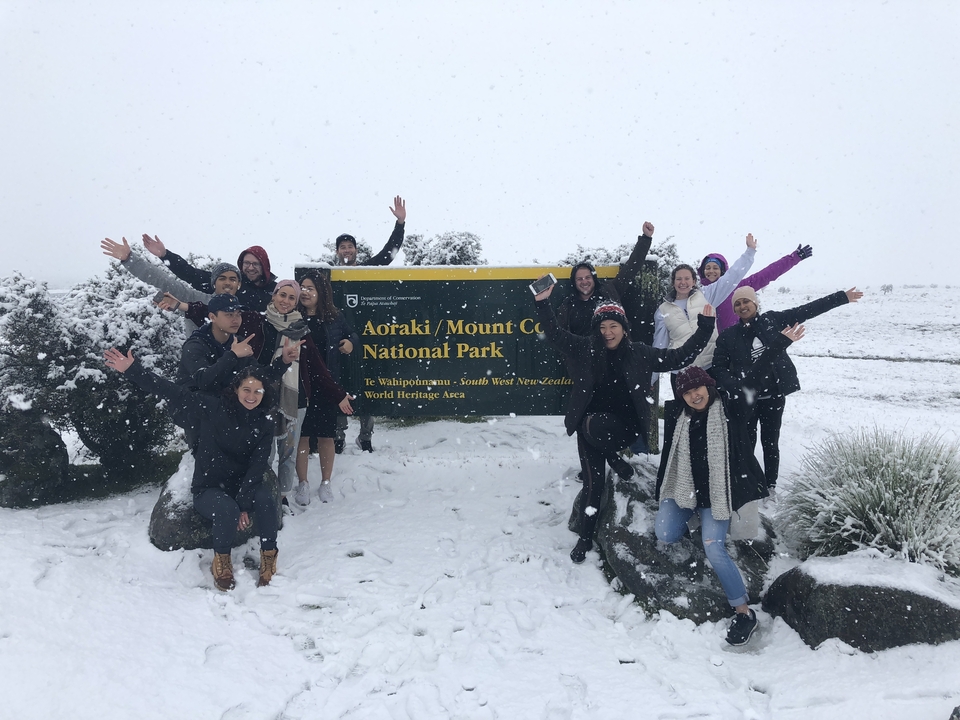 Groupe de personnes posant devant un panneau de parc enneigé.