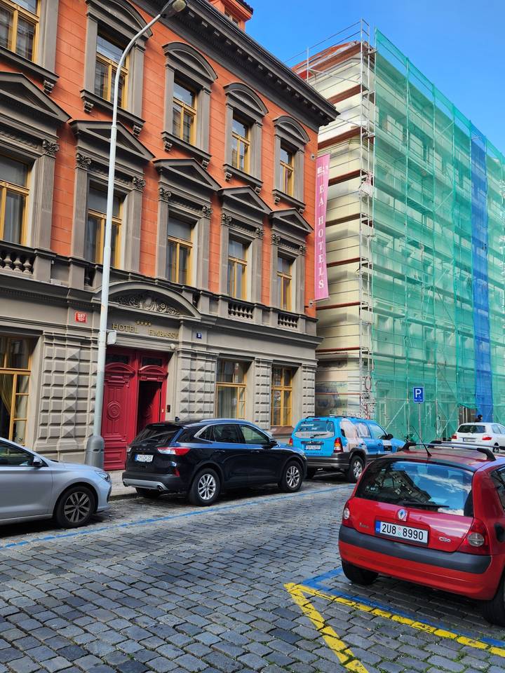 Vue de rue avec bâtiments colorés et voitures garées.