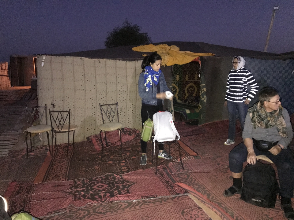 Des gens à l'intérieur d'une tente avec des tapis et des chaises.