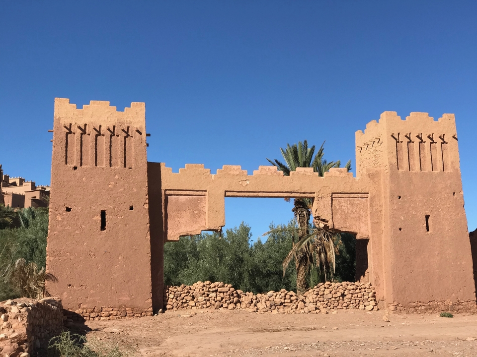 Ancienne porte fortifiée avec des palmiers en arrière-plan.