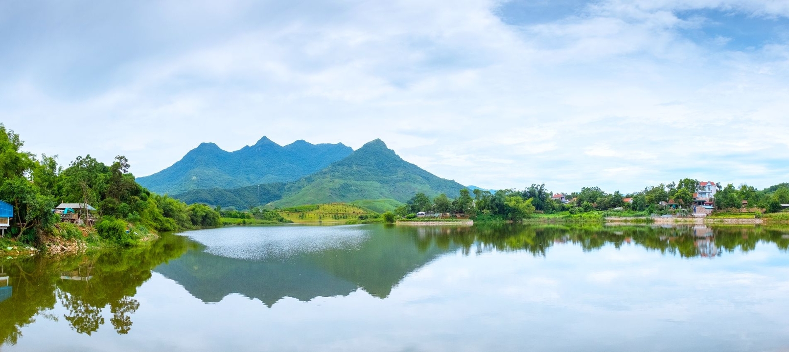 Lac avec reflets de montagnes et un ciel nuageux.
