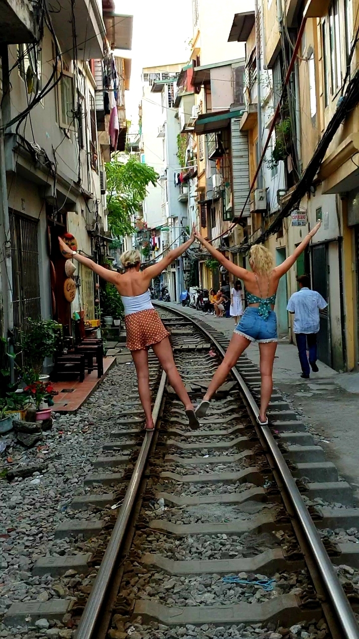 Deux personnes debout sur des voies ferrées dans une zone urbaine.