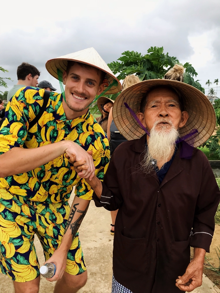 Touriste posant avec un habitant local portant un costume traditionnel.