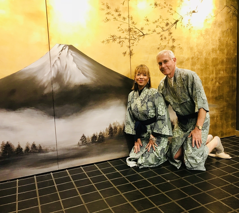 Couple en tenue traditionnelle devant une peinture de montagne.