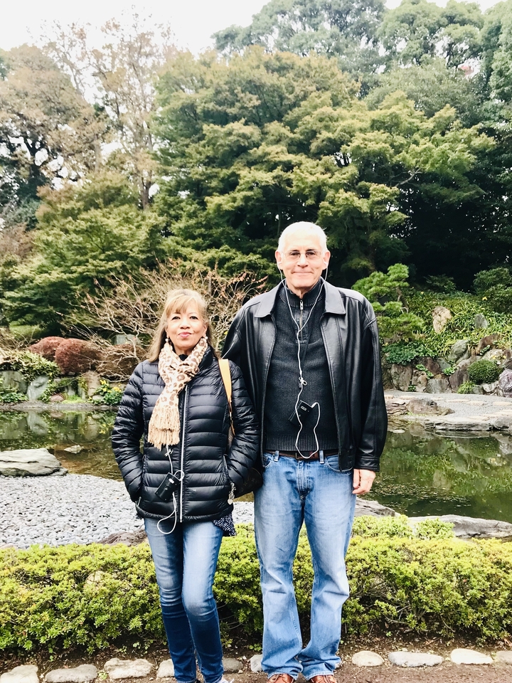 Deux personnes debout dans un jardin japonais avec un bassin et de la verdure.