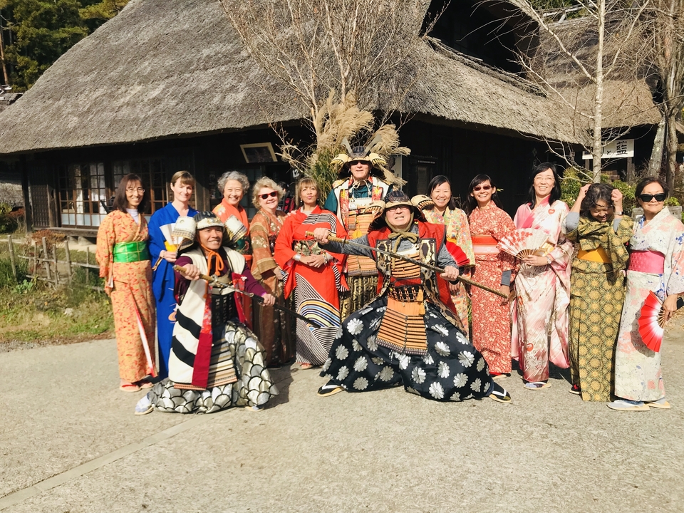 Groupe vêtu d'habits traditionnels japonais posant à l'extérieur.