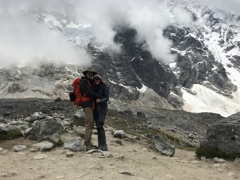 Couple debout, rapproché, dans un paysage montagneux.