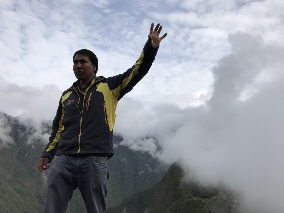 Personne faisant un geste sur un arrière-plan de montagne nuageuse.