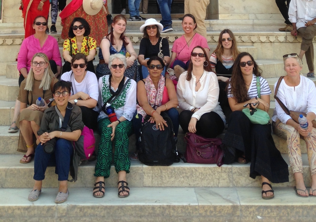 Groupe de touristes assis sur des marches historiques.