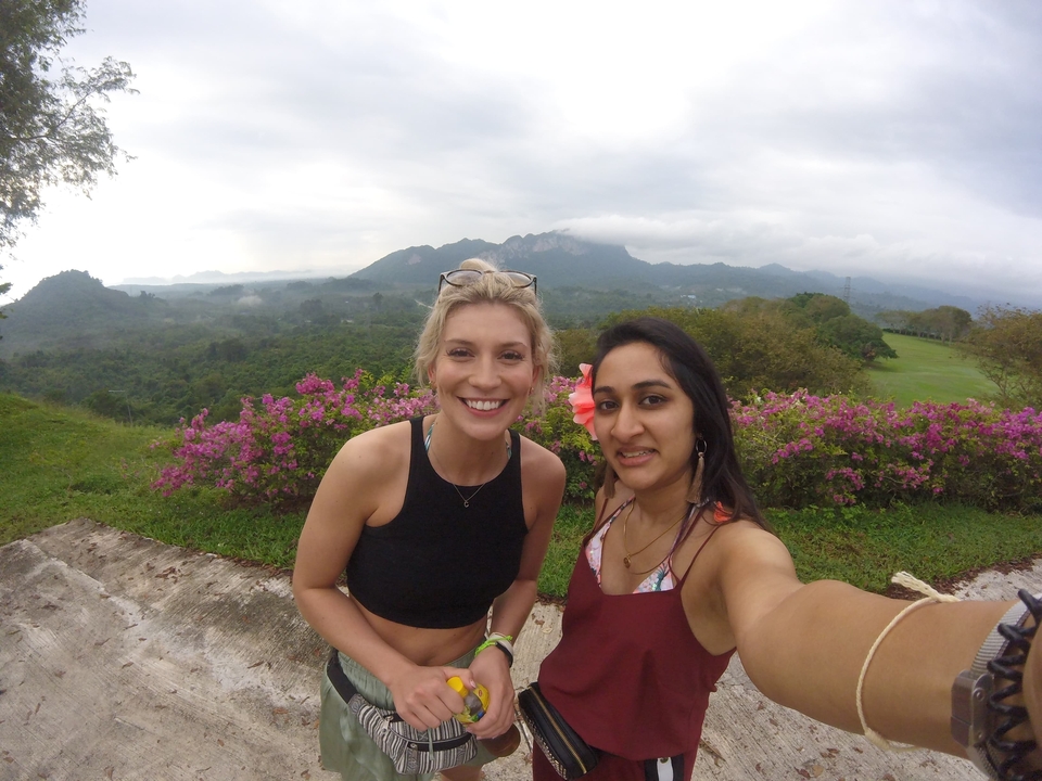Two people taking a selfie with a scenic mountain and cloud landscape.