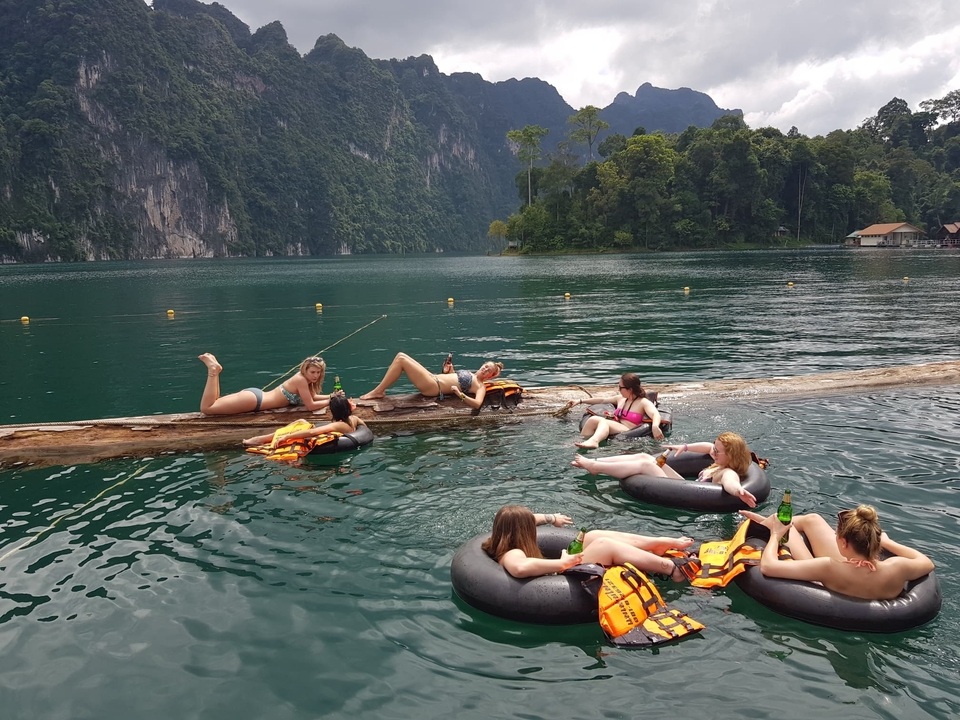 People relaxing on tubes in a lake with scenic mountains.