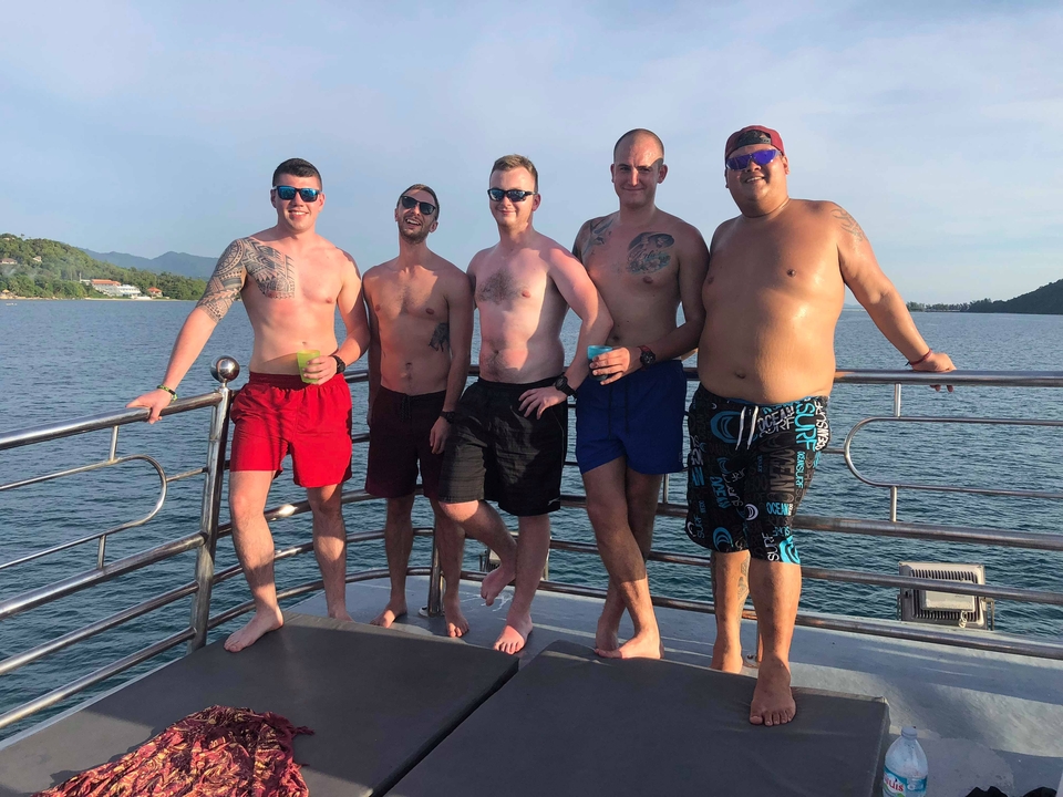 Group of men posing on a boat with a scenic view.