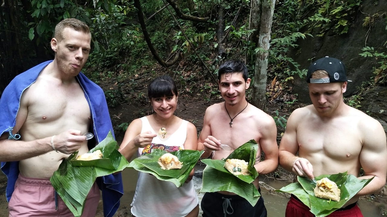 Group eating food wrapped in leaves outdoors.