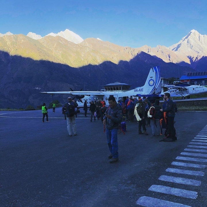 Voyageurs et avions sur le tarmac d'un aéroport dans les montagnes.