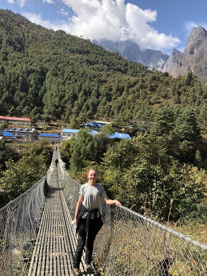 Personne debout sur un pont suspendu dans une région montagneuse.
