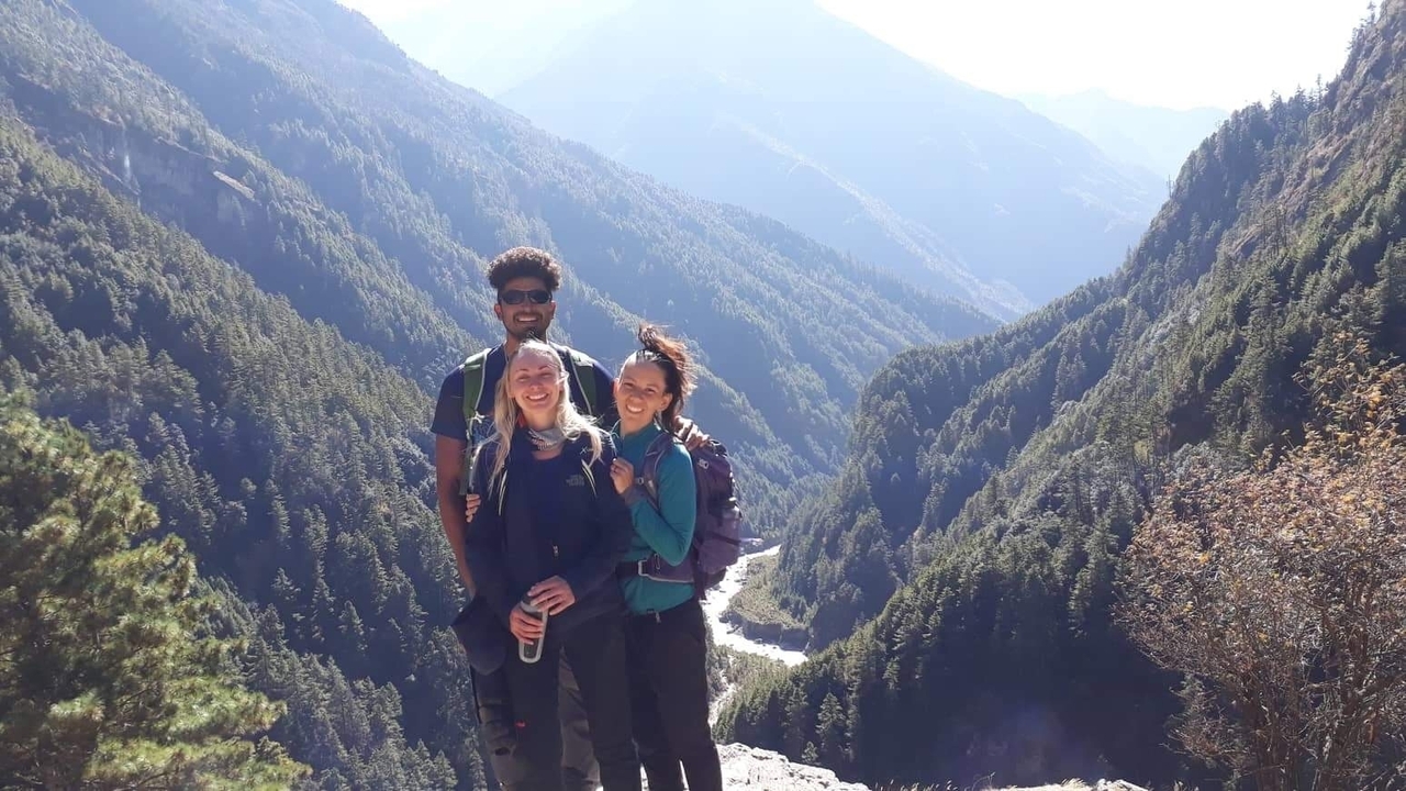 Groupe de randonneurs posant avec un paysage de vallée montagneuse en arrière-plan.