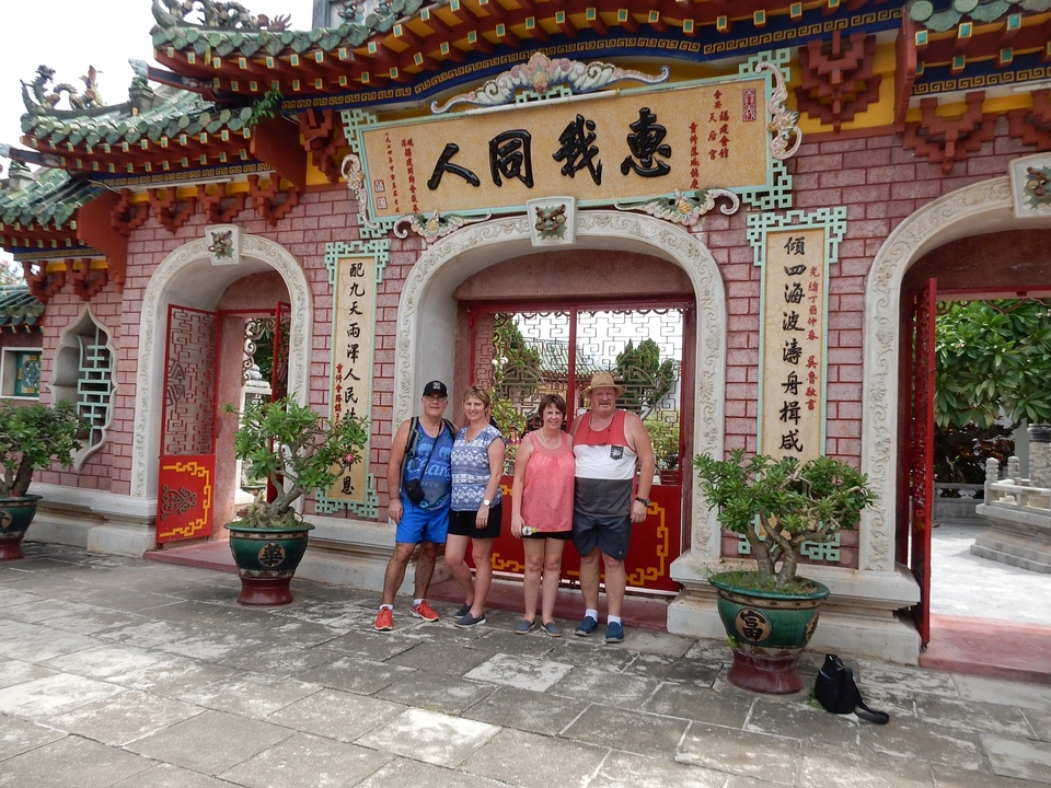 Groupe de touristes debout devant un portail orné de caractères chinois.