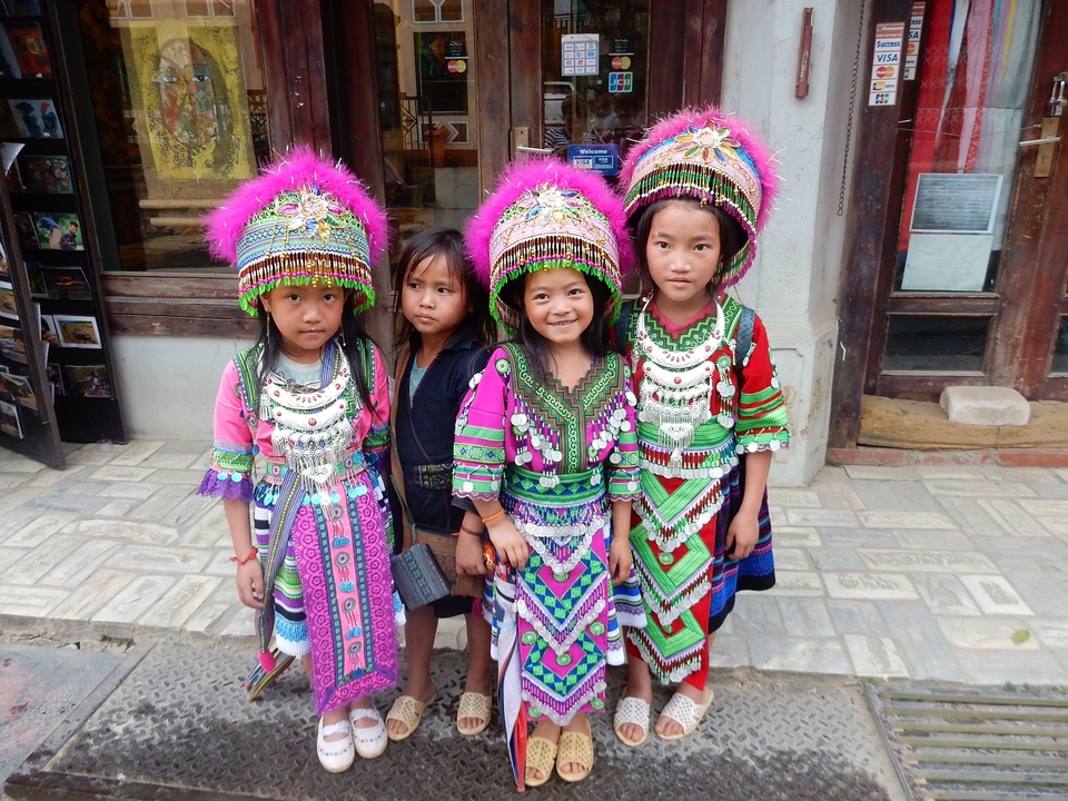 Des enfants en tenues traditionnelles colorées souriant devant l'appareil photo.